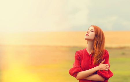 Redhead girl at meadow near wheat field