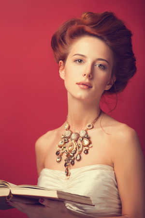 Portrait of redhead edvardian women with book on red .の写真素材