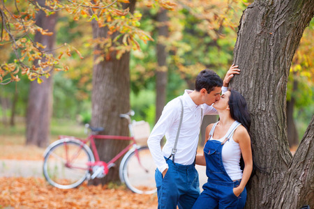 Teen couple with retro bike kissing in the park in autumn timeの写真素材