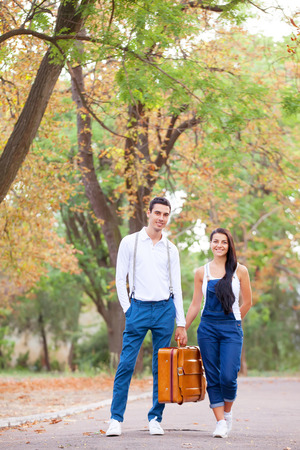 Teen couple with retro suitcase in the park in autumn timeの写真素材