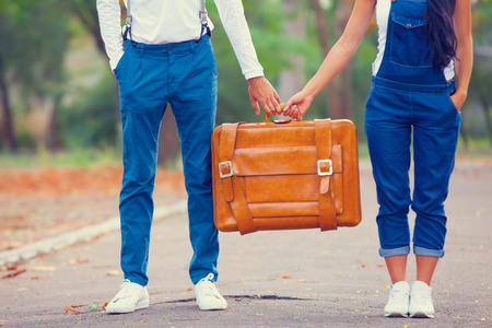 Couple holding suitcase in the park.の写真素材