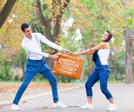 Teen couple with retro suitcase in the park in autumn timeの写真素材