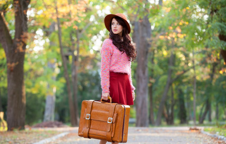 Beautiful brunette girl with suitcase in the park.の写真素材