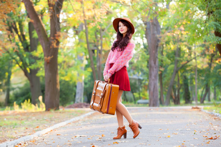 Beautiful brunette girl with suitcase in the park.の写真素材