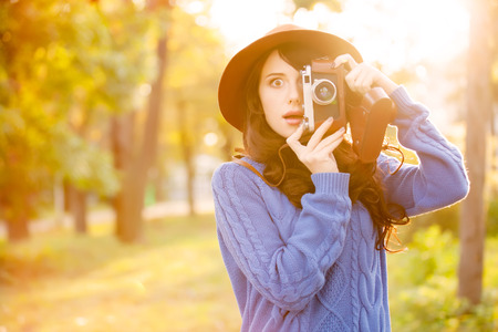 Brunette girl with camera in the park in sunset timeの写真素材