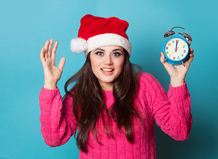 Brunette girl with alarm clock on blue background.の写真素材