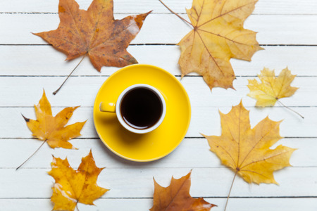 Cup of coffee and leafs on wooden table.の写真素材