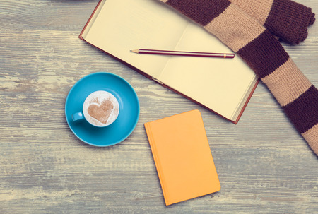 Cup, croissant and book with scarf on wooden table.の写真素材