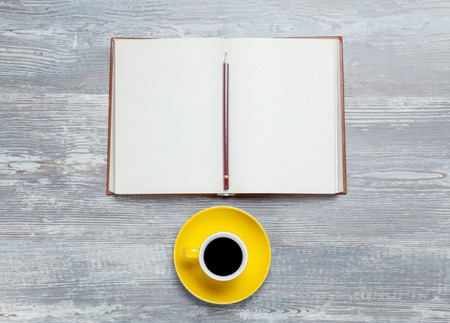 Book and cup of coffee on wooden table.の写真素材