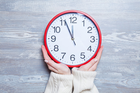 Female hands holding clock on a table.の写真素材