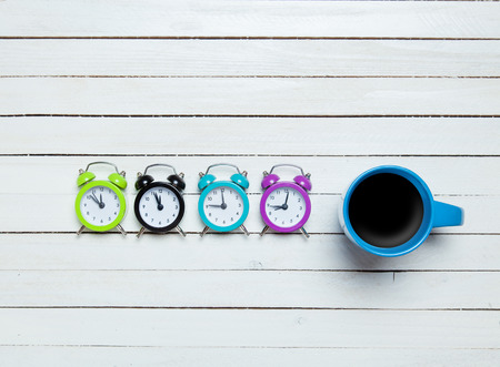 Four alarm clocks and cup of coffeeの写真素材