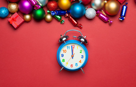 Alarm clock and christmas toys on red table.