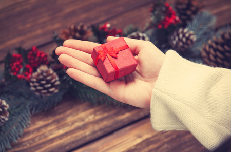 Female hand with gift box and pine branches.の写真素材