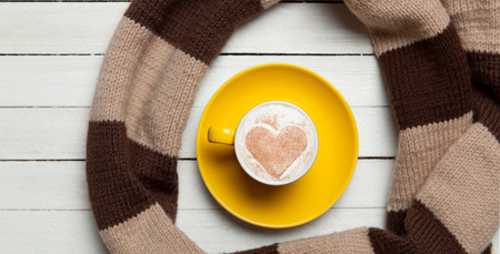 Cup of coffee and scarf on wooden table.の写真素材