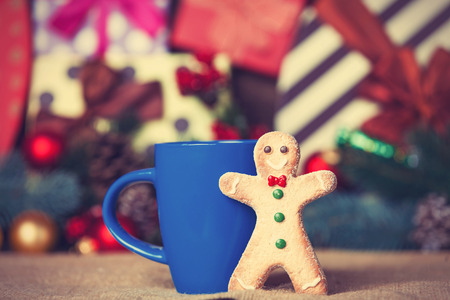 Gingerbread man near cup and christmas gifts on background.の写真素材