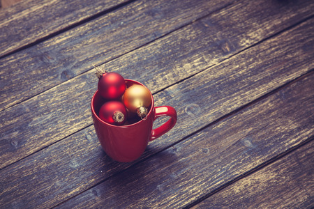 Cup with christmas balls on wooden table.の写真素材