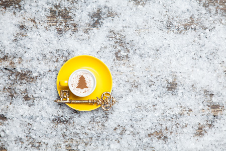 Cappuccino with christmas tree shape and key on artificial snow backgroundの写真素材