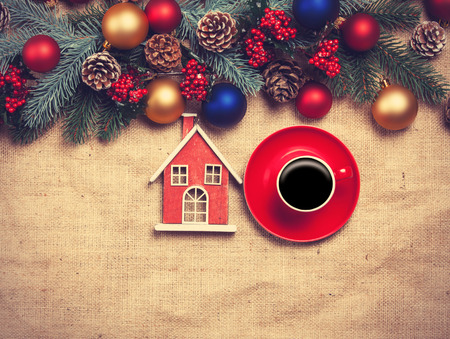 Hot coffee and toy home on a table near pine branchesの写真素材