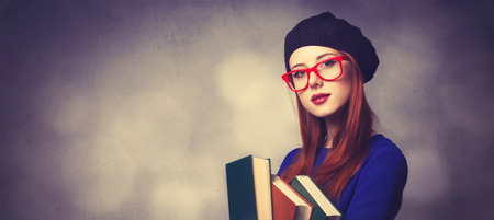 Portrait of beautiful girl in blue dress with books and bokeh on background.の写真素材
