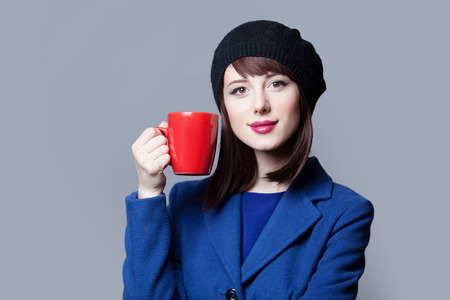 Portrait of beautiful women in blue dress with red cup on grey background.の写真素材