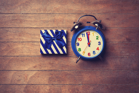 color gift box and alarm clock on wooden background