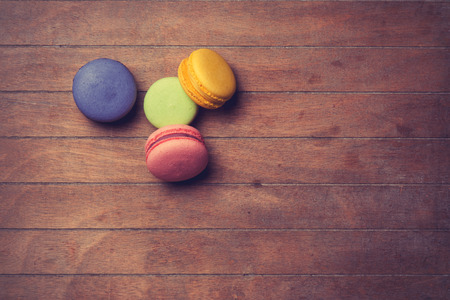 Color macarons on wooden background. Photo in old color image styleの写真素材