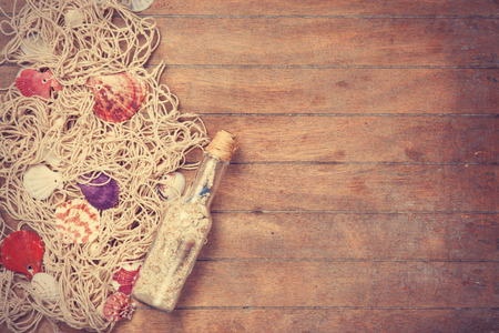 Net and shells with bottle on wooden background.の写真素材
