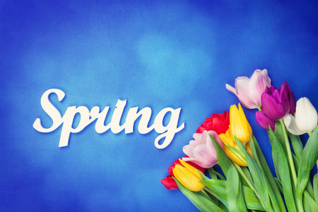 Bouquet of tulips and word Spring on wooden background.