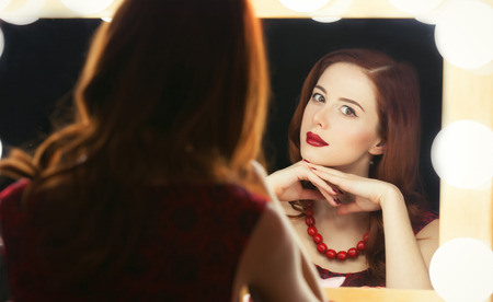 Portrait of a beautiful woman as applying makeup near a mirror.の写真素材