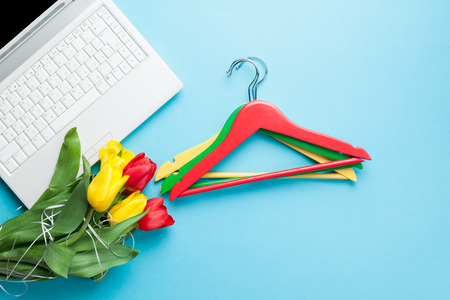 White computer and bouquet of tulips with hanger on blue backgroundの写真素材