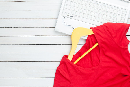 White computer with hanger and dress on white wooden ackgroundの写真素材