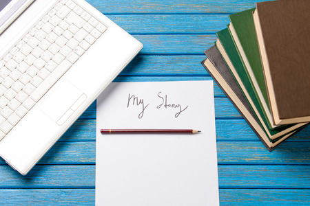pencil and paper with My Story words near notebook on blue wooden tableの写真素材