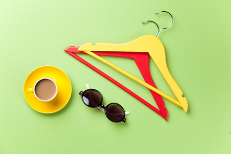 Cup of coffee and hangers with sunglasses on green background.の写真素材