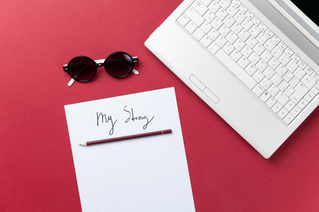 Sunglasses and paper near notebook on red backgroundの写真素材