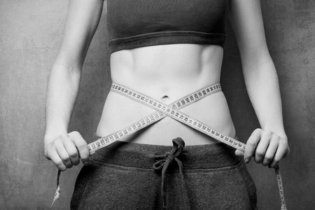 Woman showing her abs with metric after weight loss on backgroundの写真素材