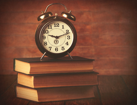 Books with retro alarm clock on wooden background.の写真素材