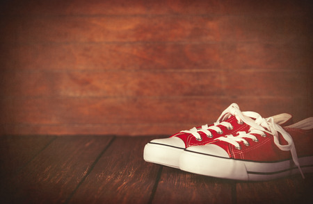 Red gumshoes on wooden table and background.の写真素材