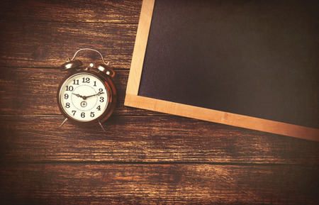 Retro alarm clock and blackboard on wooden backgorund.の写真素材