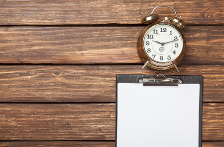 Alarm clock and business tablet on wooden table. Above view.の写真素材