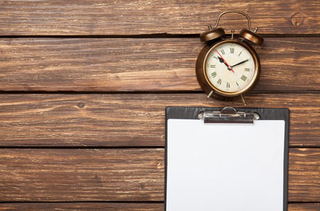 Alarm clock and business tablet on wooden table. Above view.の写真素材