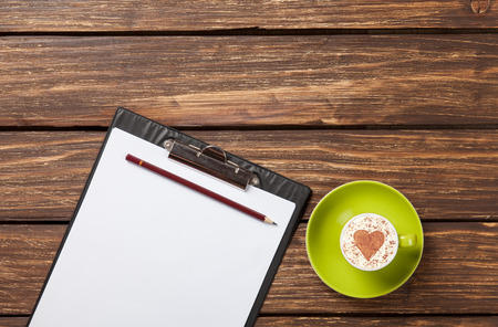 Cappuccino and business tablet with paper on wooden table.の写真素材