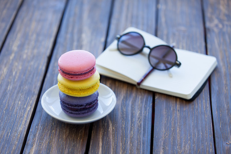Macarons and little notebook with glasses on wooden table.の写真素材