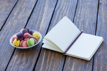 Macarons and little notebook on wooden table.の写真素材