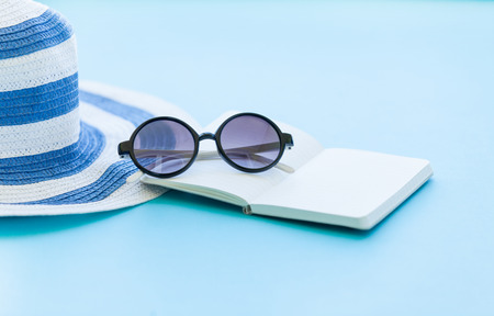 Sunglasses and hat with notebook on blue backgroundの写真素材