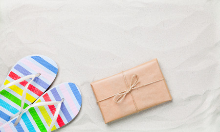 Colorful flip flops and classic pacakge on white sand. Photo with high angle view.の写真素材