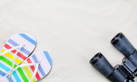 Colorful flip flops and classic binocular on white sand. Photo with high angle view.の写真素材