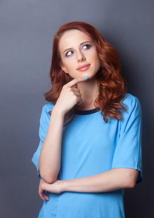 Portrait of a beautiful redhead girl in blue dress on grey backgroundの写真素材