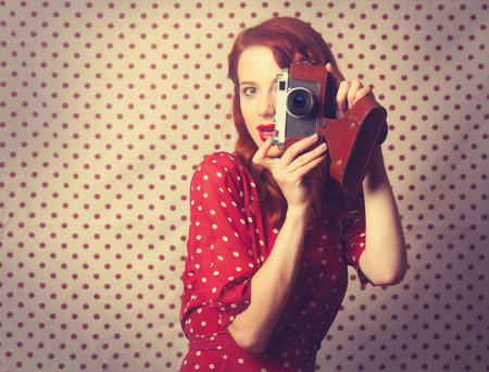 Portrait of redhead girl with retro camera on Polka dot background.の写真素材