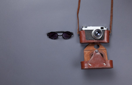 glasses and retro camera in leather case lying down on grey backgroundの写真素材