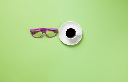Cup of coffee and glasses on green backgroundの写真素材